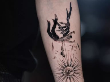 Intricate tattoo featuring a diver and sun design on an arm