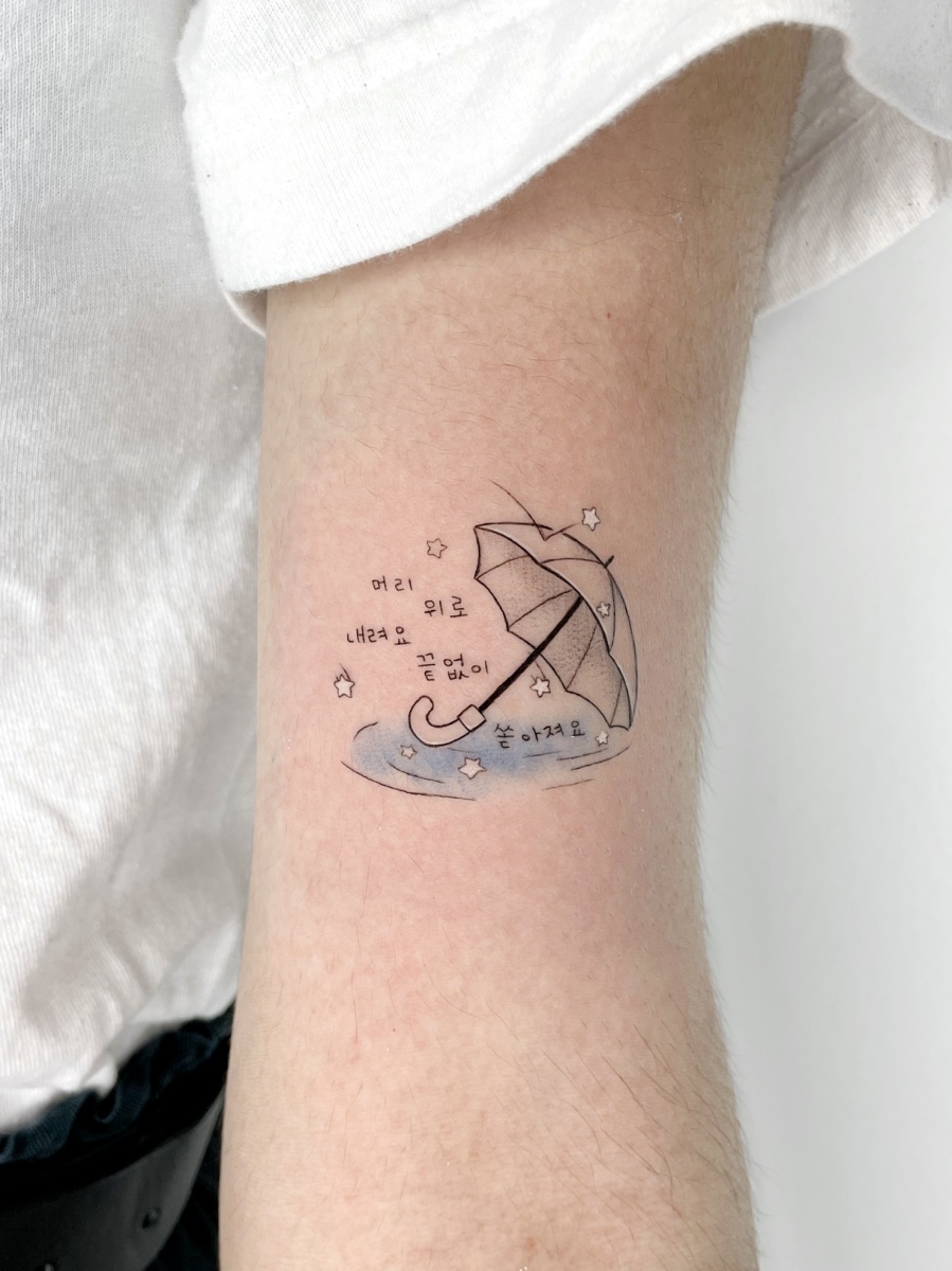 Tattoo of an umbrella over water, with text in Korean