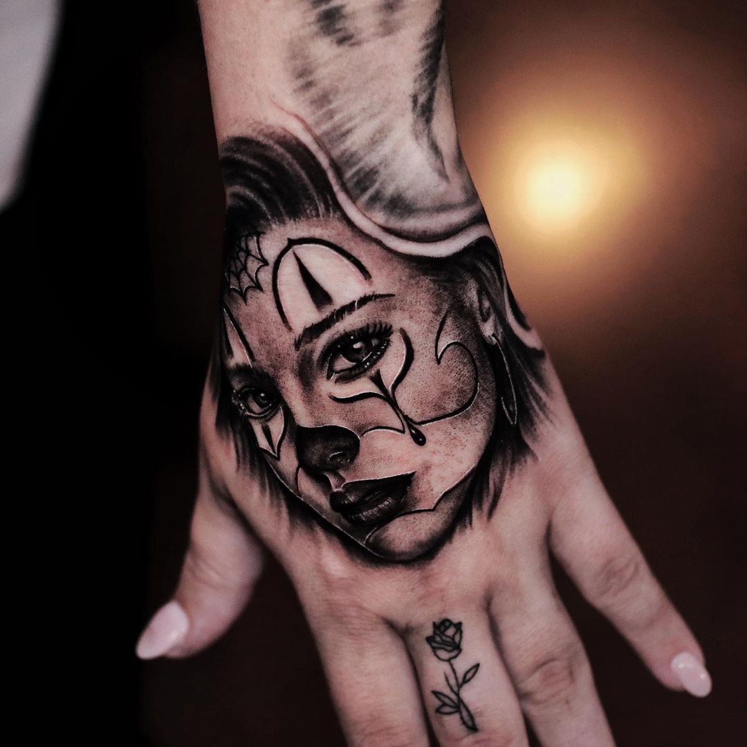Black and grey tattoo of a woman's face on a hand