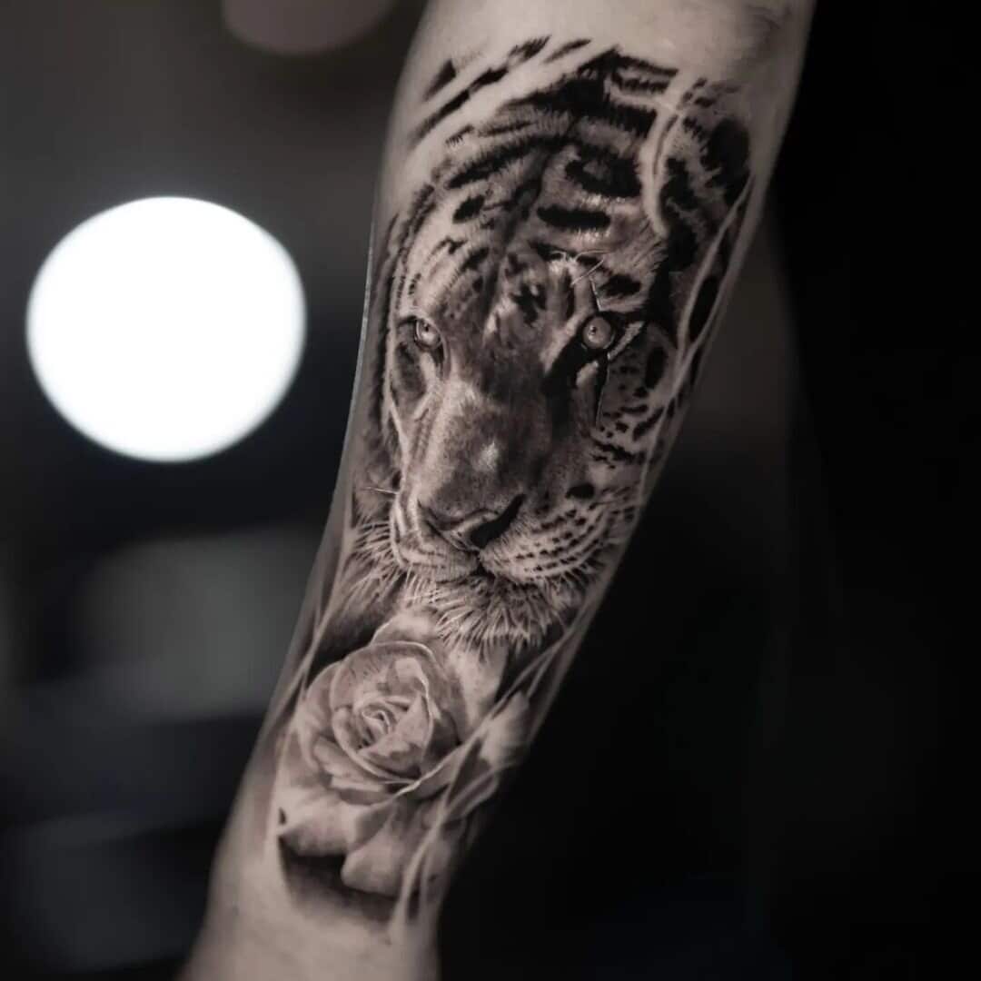 Realistic tattoo of a tiger and a rose on arm