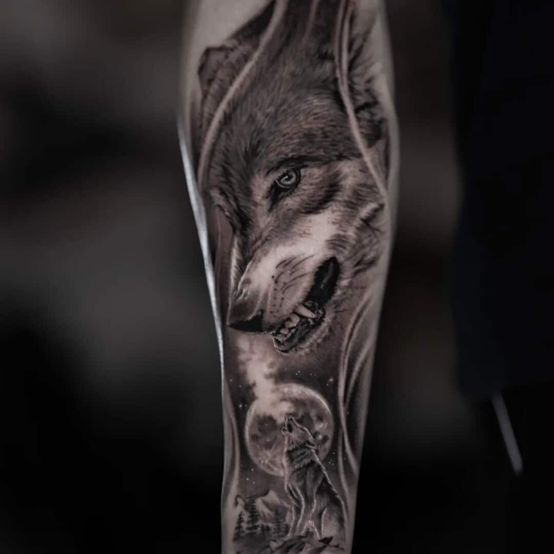 Intricate wolf tattoo on forearm with moon and landscape.