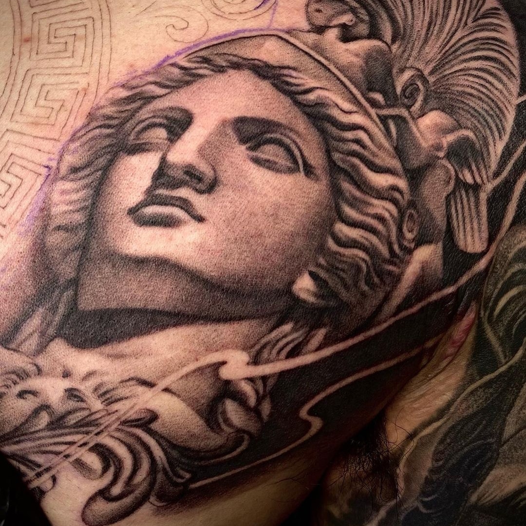 Close-up of a detailed tattoo featuring a classical statue's face