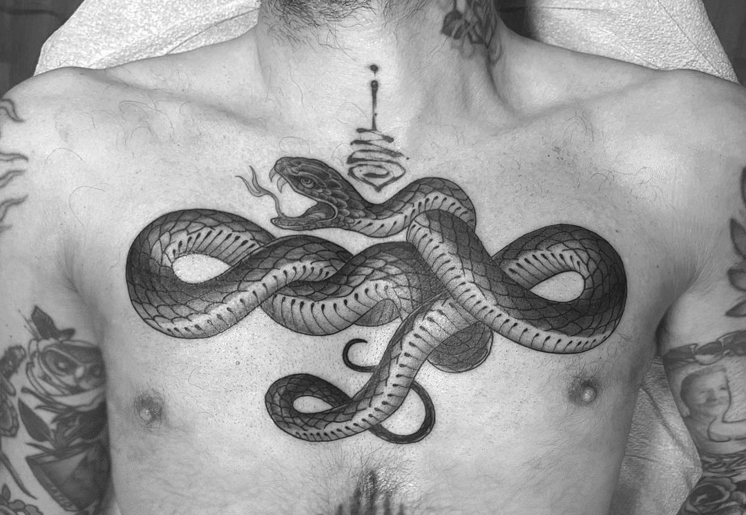 Black and white tattoo of a snake on a man's chest