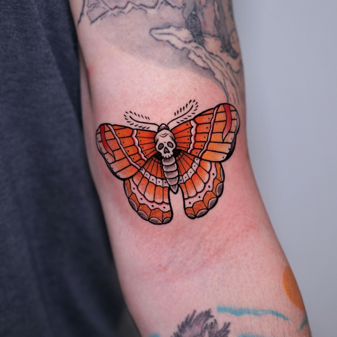 Colorful butterfly tattoo with a skull design on arm