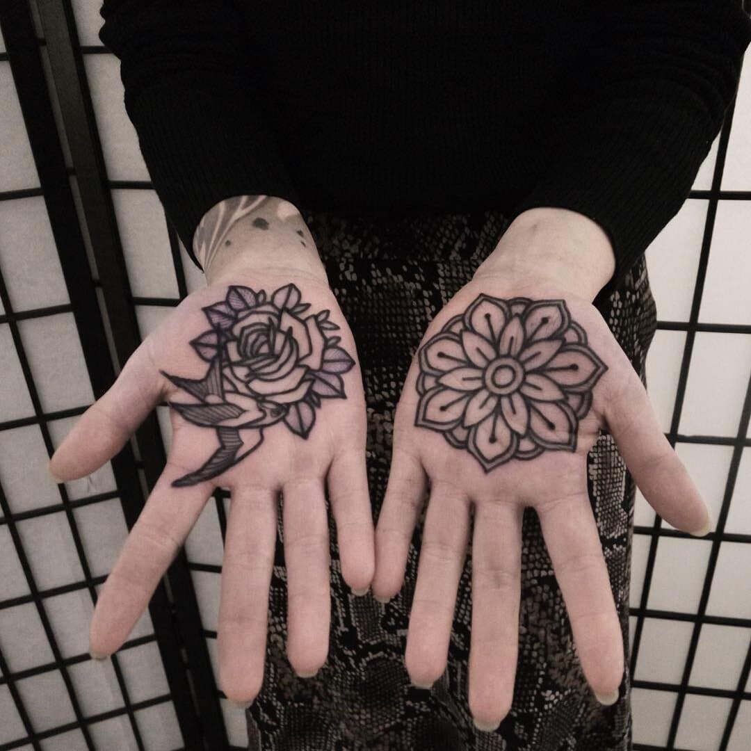 Hands with floral tattoos, one rose and one flower design