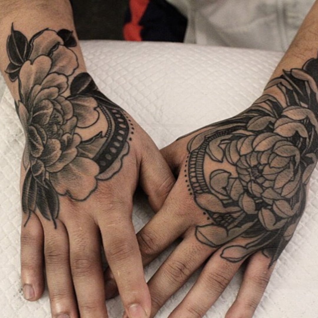 Close-up of tattooed hands with floral designs.