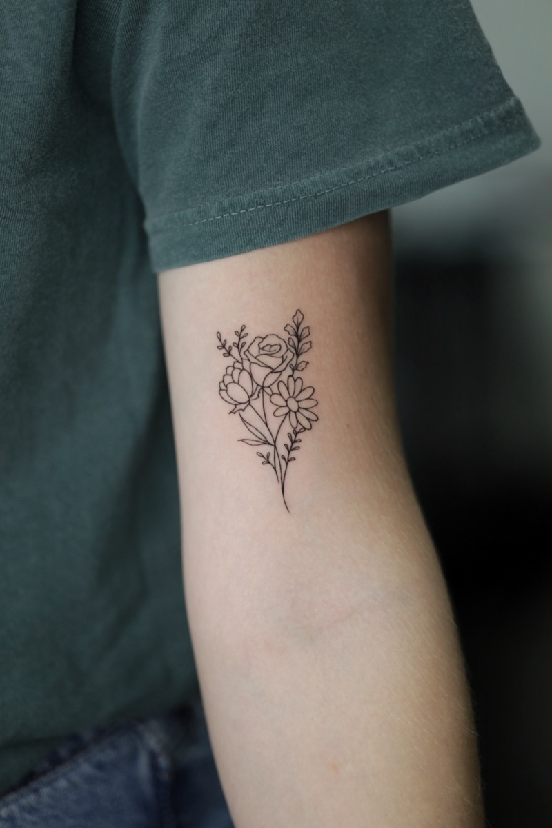 Florally designed tattoo on an arm with a dark green shirt.
