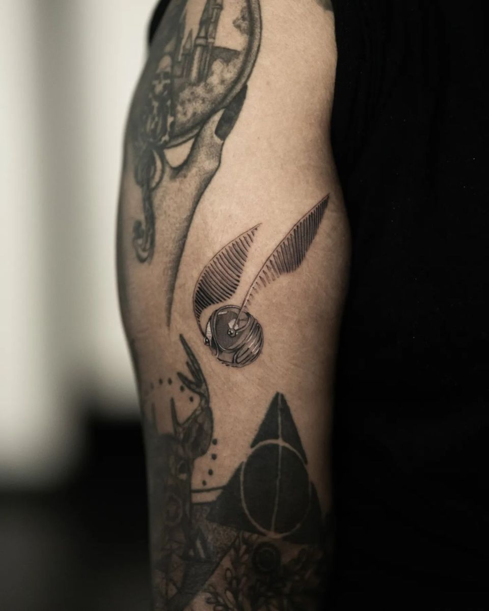 Detailed tattoo design on an arm featuring a bird and a sphere.