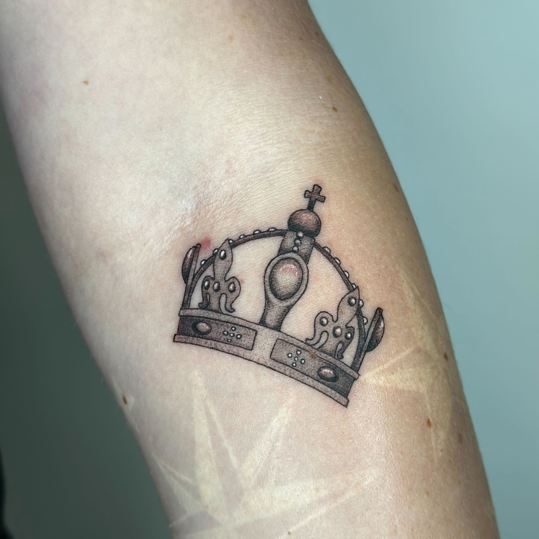 Tattoo of a detailed crown design on a forearm.