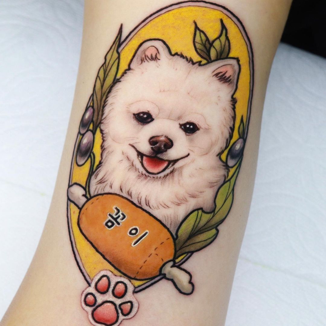 Tattoo of a fluffy white dog with an orange bone and leaves