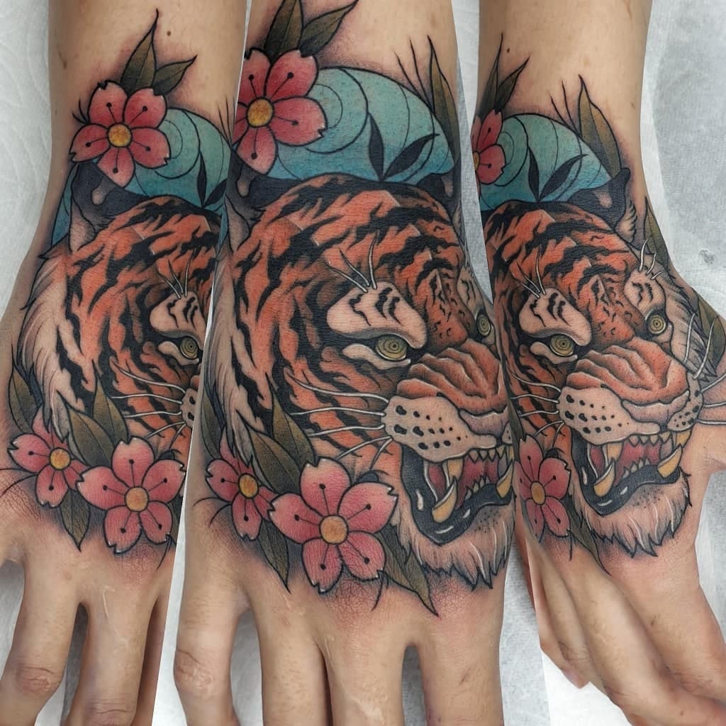 Colorful tiger tattoo featuring flowers on hands.