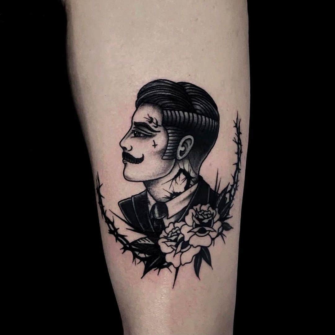 Black and grey tattoo of a suited man with a mustache and roses.